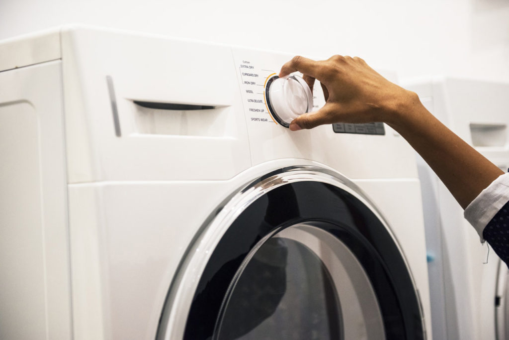Hand dialing a setting on a front-load dryer. Save money in your Asheville home.
