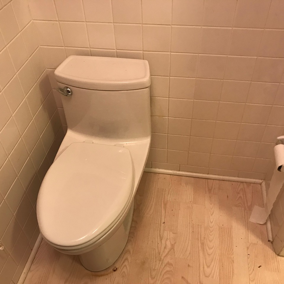 Toilet installed against a wall with no leg room to one side.